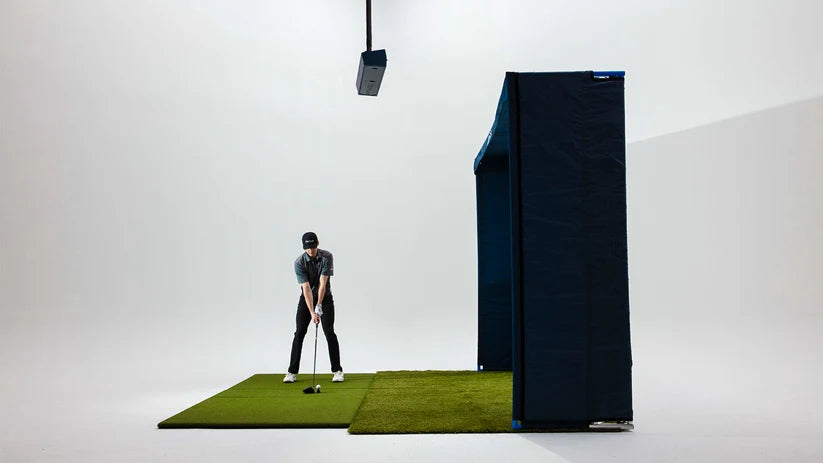 Person practicing golf swings on a simulator with a black screen in the background