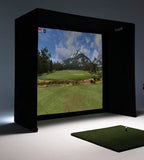 A black TigoGolf virtual reality golf simulator setup with a large screen displaying a mountain golf course and a green turf hitting mat in the foreground.