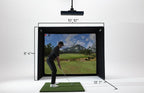 A golf simulator setup shown in a studio with dimension labels: a black enclosure, a suspended impactor, a green turf mat, and a golf course scene displayed on the screen. A person is visible inside the simulator, and measurement lines annotate the enclosure dimensions.